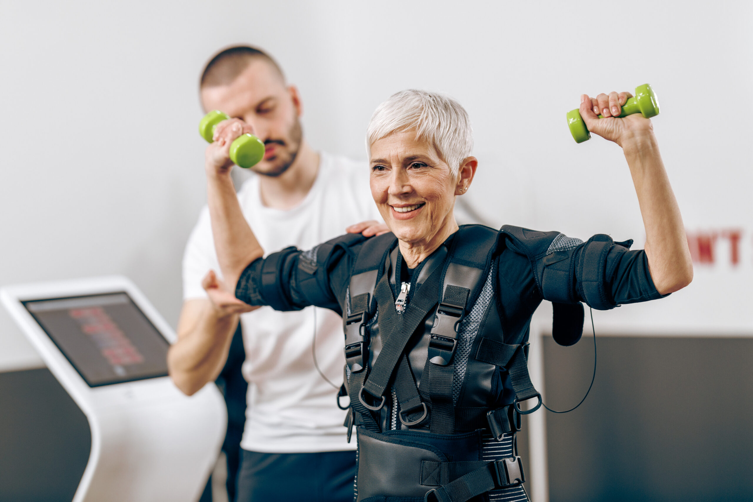 Senior woman is doing EMS training with coach in the gym.